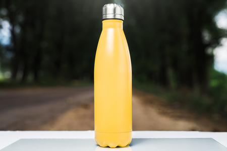 Stainless  water bottle on white table, outdoor. Yellow colorの写真素材