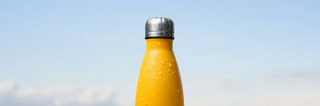 Stainless bottle, sprayed with water. Sky and forest on background.の写真素材