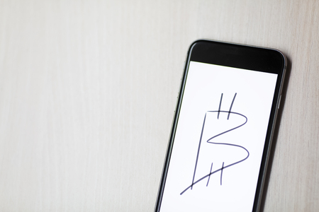 Bitcoin symbol, painted on smartphone display, white background.の写真素材
