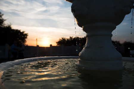 Little fountain on the background of a beautiful sunsetの写真素材