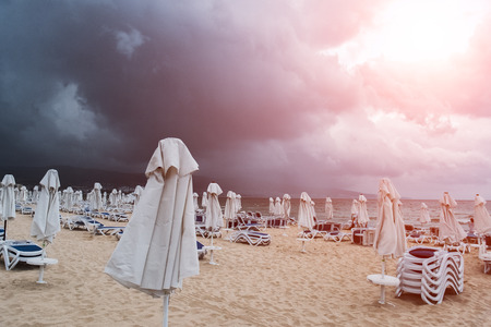 Empty beach with lounge chairs and umbrellas before the rain in summer seasonの写真素材
