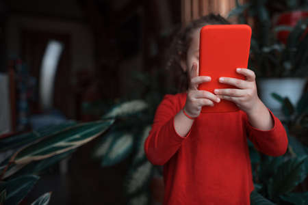 Little kid girl in red use smartphoneの写真素材
