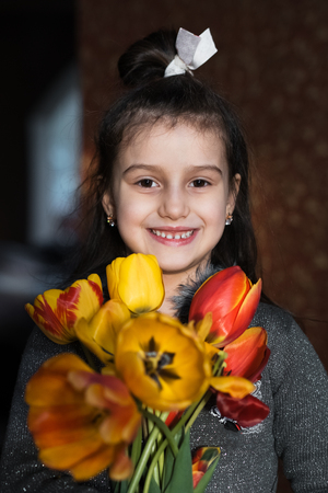 Smiling kid girl with colorful tulips in handsの写真素材