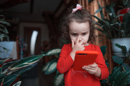Little kid girl in red use smartphoneの写真素材