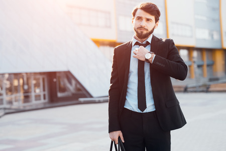 Hipster bearded businessman in suit straightens his tie outdoorの写真素材