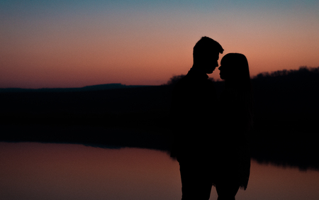 Silhouette of young couple on background of sunset.