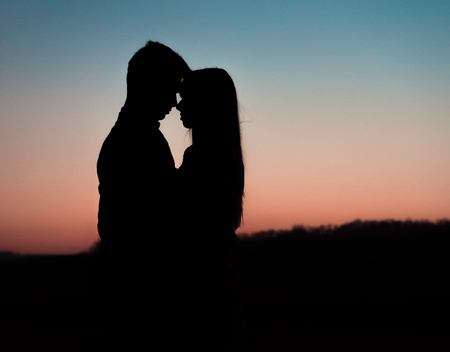 Silhouette of young couple on background of sunset.