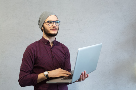 Young bearded hipster holding laptop in hands.の写真素材