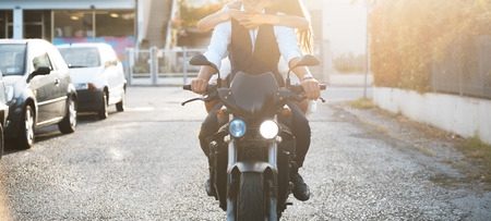Young couple riding a modern motorcycle at sunset.の写真素材