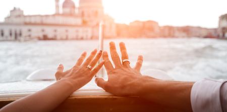 Wedding couple hands with engagement rings over lake background. Italy, Veniceの写真素材