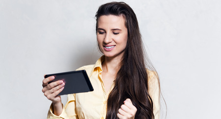 Portrait of young smiling girl using smartphone over white studio background.の写真素材