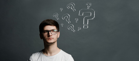 Portrait of thinkng young guy with question mark above his head.