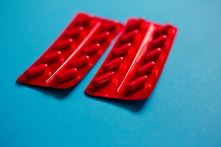Medicine pills capsules, red pack over blue.