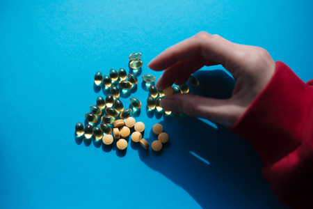 Taking vitamine medicine pills over blue background.