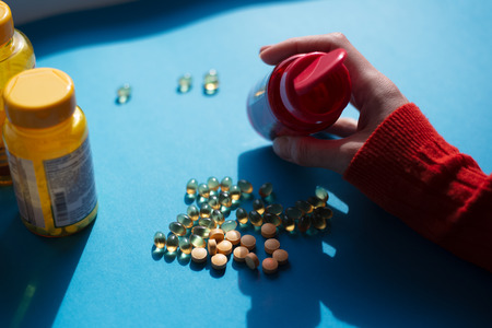 Taking vitamine medicine pills over blue background.
