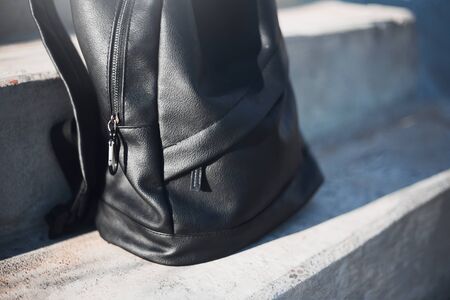 Close-up of black backpack on urban stairs.の写真素材