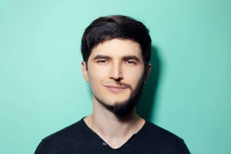 Studio portrait of young man with half shaved face on background of aqua menthe color.
