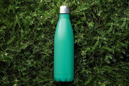 Top view of reusable steel thermo water bottle with mockup on green grass, aqua menthe color.の写真素材