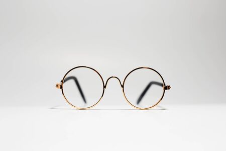 Close-up of round gold eyeglasses isolated on white.