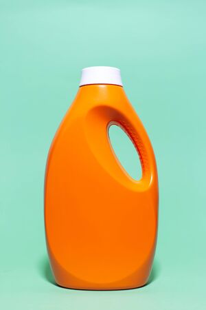 Close-up of orange detergent bottle with mockup on background of aqua menthe color.の写真素材
