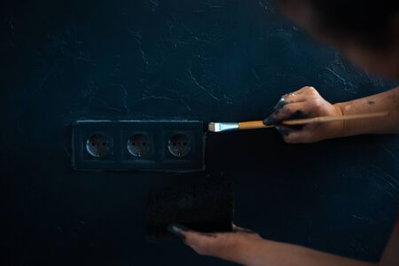Close-up of female hands with brush paint power socket with black color.の写真素材