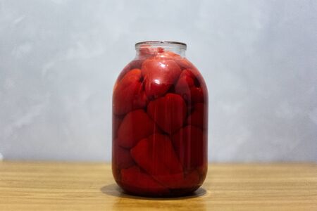 Close-up of glass jar with big red paprika peppers.