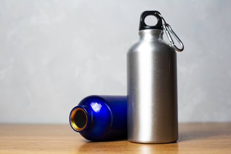 Silver and shiny blue thermo bottle on wooden table.の写真素材
