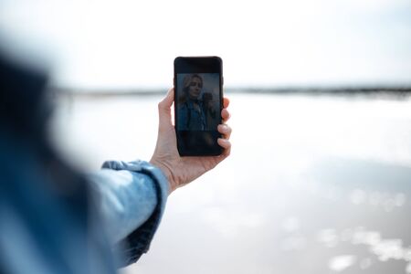 Close up of young girl taking selfie on the beach.の写真素材