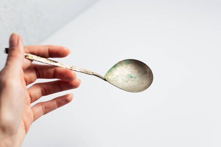 Female hand hold ancient spoon on white background.の写真素材