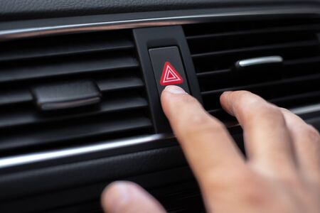 Close-up of male hand, presses the emergency button in car.
