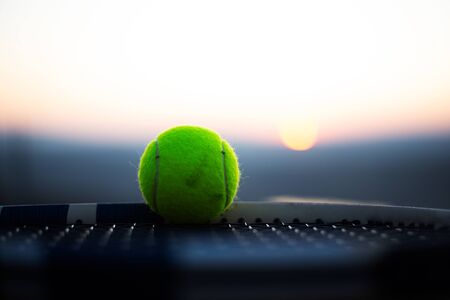Close-up of tennis ball on net of racket at sunset.の写真素材