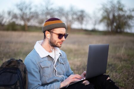 Portrait of young hipster man using laptop outdoor.の写真素材
