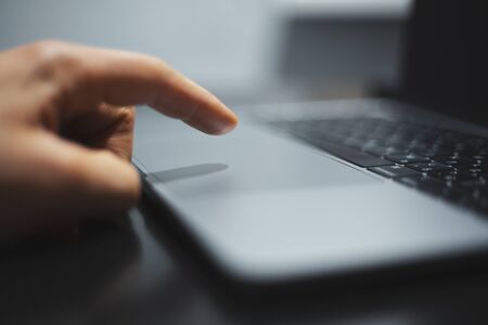 Close-up of male hand touching with finger laptop touchpad.の写真素材