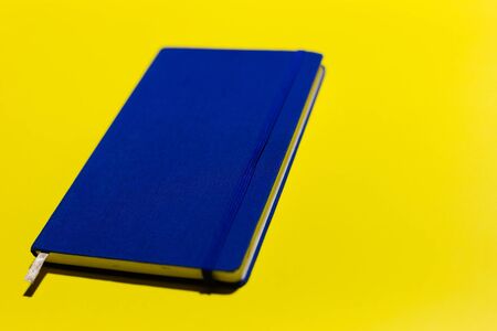 Close-up of blue notebook on yellow background.