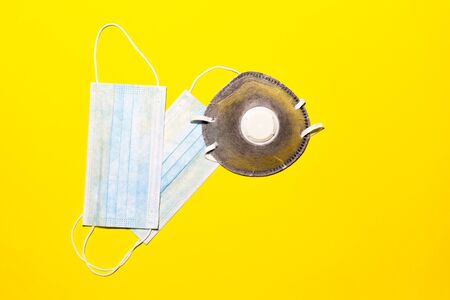 Close-up of surgical and protective flu or another virus mask. Top view, background of yellow color. Safety concept.の写真素材