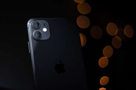 Moldova, Chisinau - 03.11.2019: Close-up of black iPhone 11 on dark wooden table.