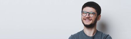 Panoramic banner, studio portrait of young happy man wearing round eyeglasses on white background with copy space.の写真素材