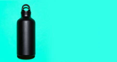 Black aluminum reusable thermo water bottle on cyan background with copy space.の写真素材