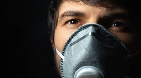 Coronavirus prevention. Close-up portrait of young guy wearing protective medical respiratory mask...