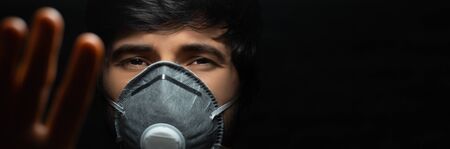 Coronavirus prevention. Close-up portrait of young guy wearing protective medical respiratory mask...