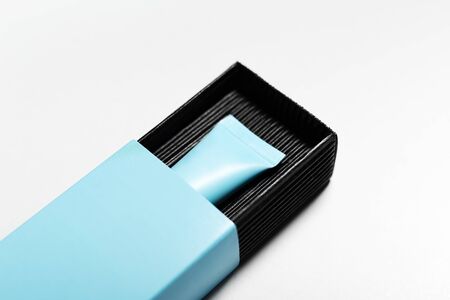 Close-up of cosmetic cyan tube with mock-up, packaging in black and blue box on white background.の写真素材