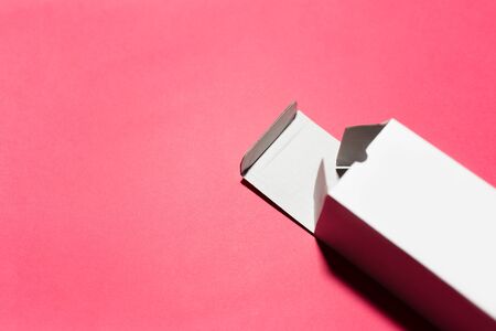Close-up of opened cardboard white box isolated on studio background of pastel coral pink color.