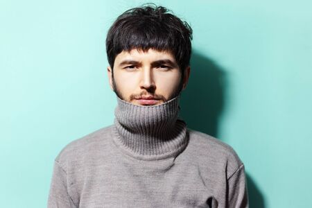 Studio portrait of young guy wearing sweater on background of aqua menthe color.の写真素材