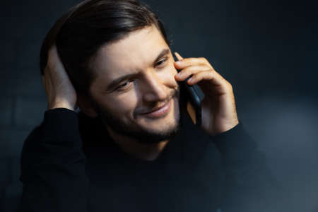 Close-up portrait of smiling young man, talking on the smartphone.