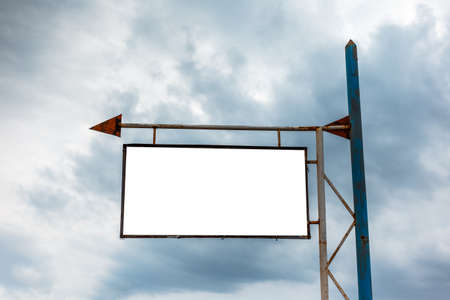 Old empty billboard for advertising poster with arrow sign on the background of  rainy cloudy sky.の写真素材