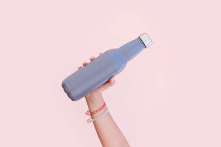 Close-up of female hand holding a eco reusable steel stainless thermo water bottle on the background of pastel pink color.の写真素材