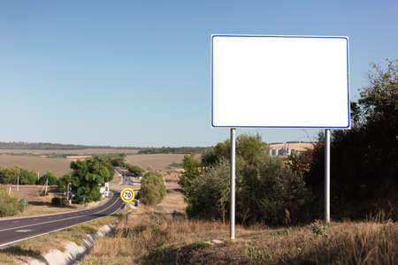 Empty billboard for advertising poster near asphalting road. Background of blue sky and beautiful nature.の写真素材