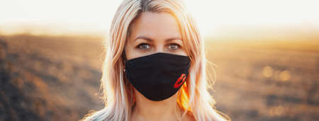 Outdoors portrait of woman wearing respiratory face mask against coronavirus and covid-19 on...