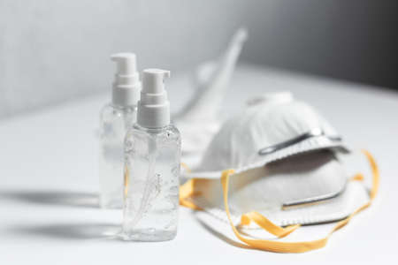 Coronavirus/covid-19 prevention. Close-up of two bottles with sanitizer antiseptic gel near medical flu masks on white table.の写真素材