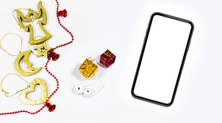 Top view of smartphone with mockup near wireless earphones and gift boxes and decoration. Christmas...